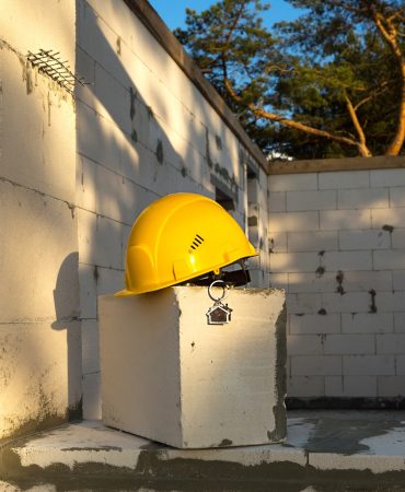 construction-yellow-hardhat-and-key-to-house-on-wi-XKS8L3W